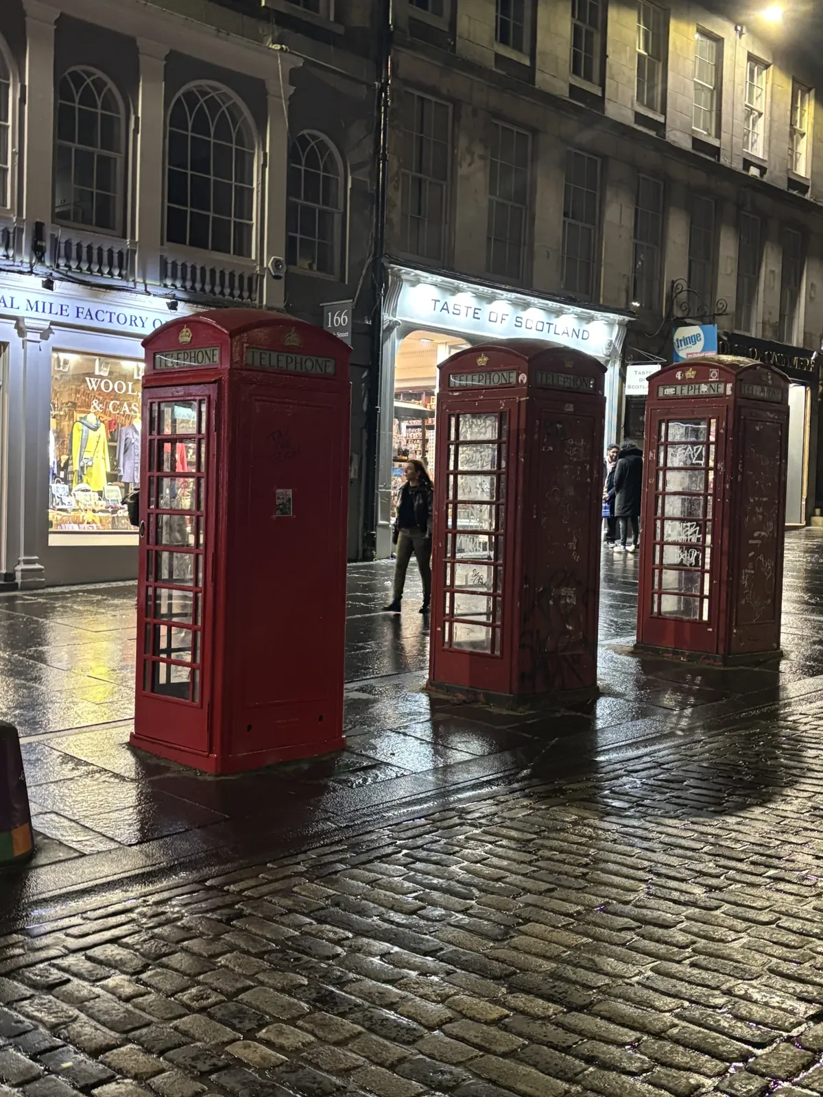 Trois cabines rouges sur les pavés mouillés.