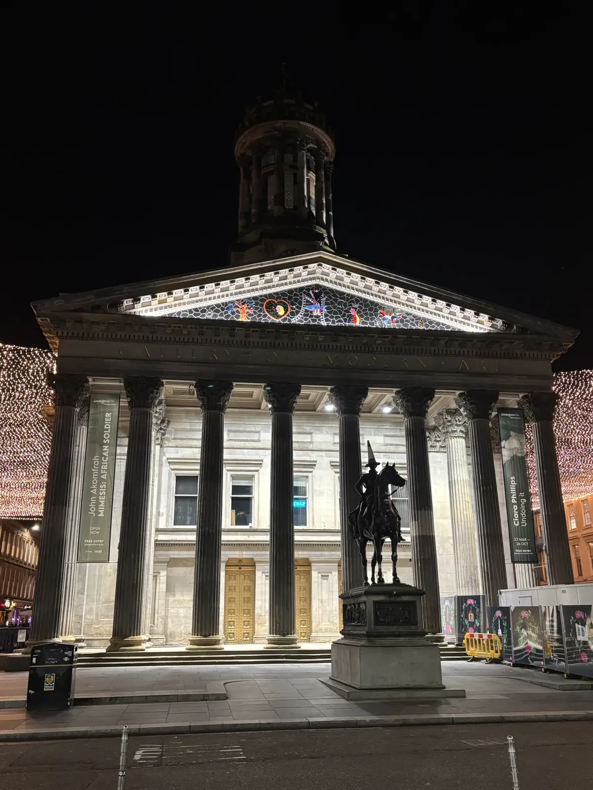La GoMA de Glasgow, la nuit, avec la statue au cône sur la tête.