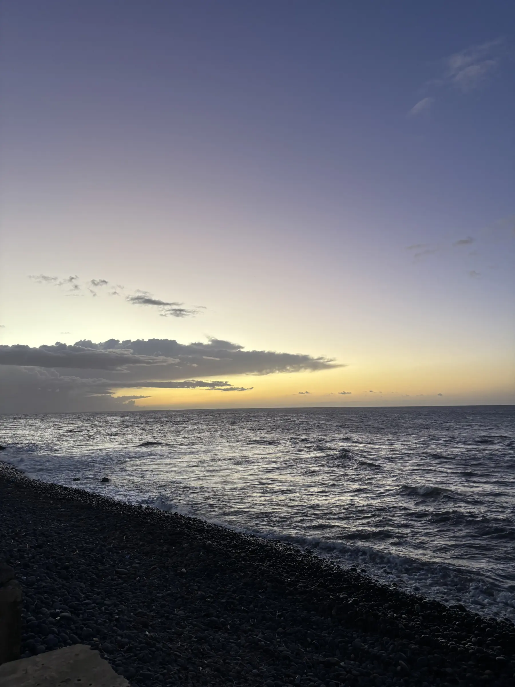 Côte est : galets noirs, houle et lumière qui tombe.